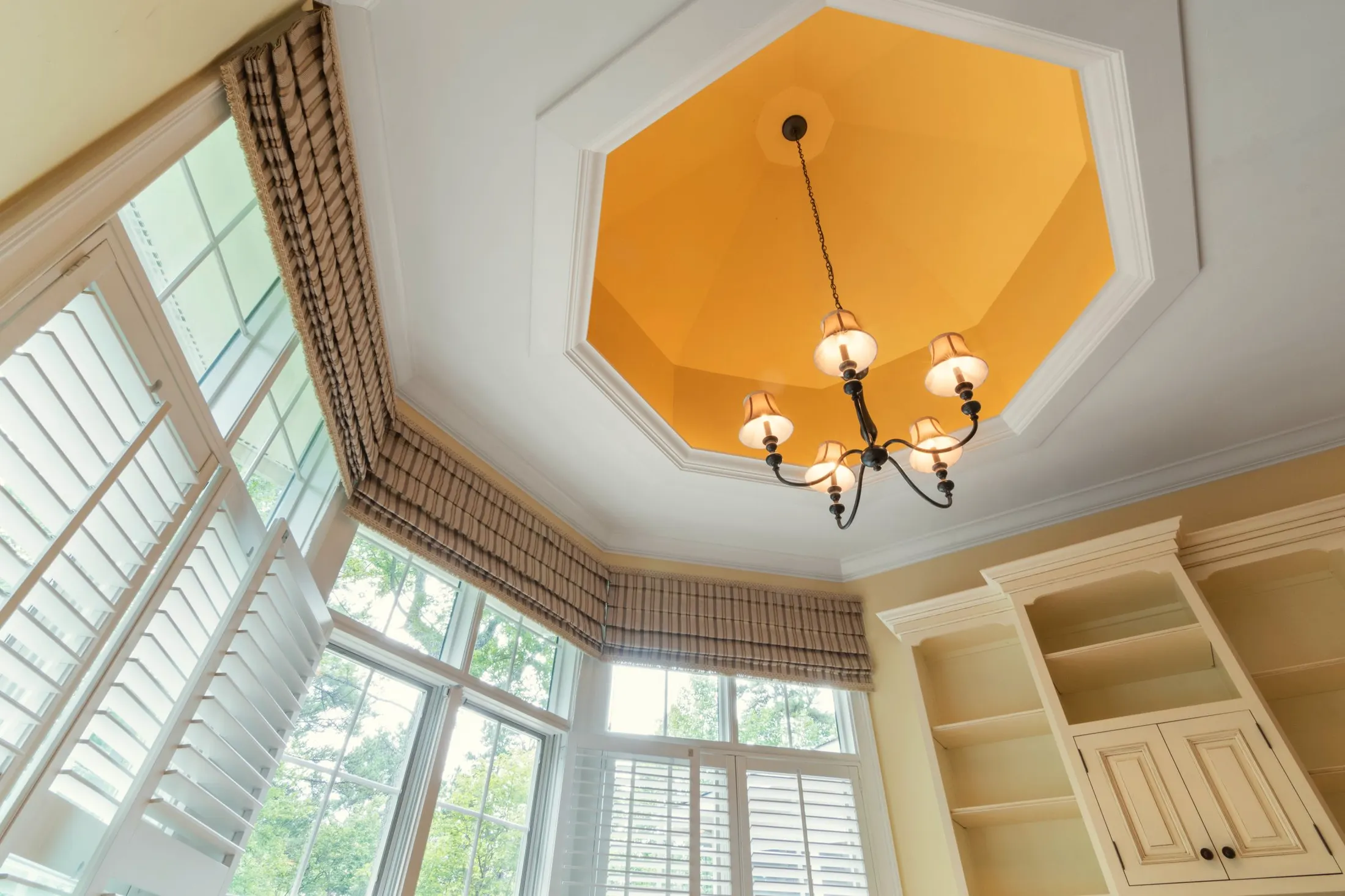 Sunny breakfast bay with tall windows, plantation shutters and a painted tray ceiling