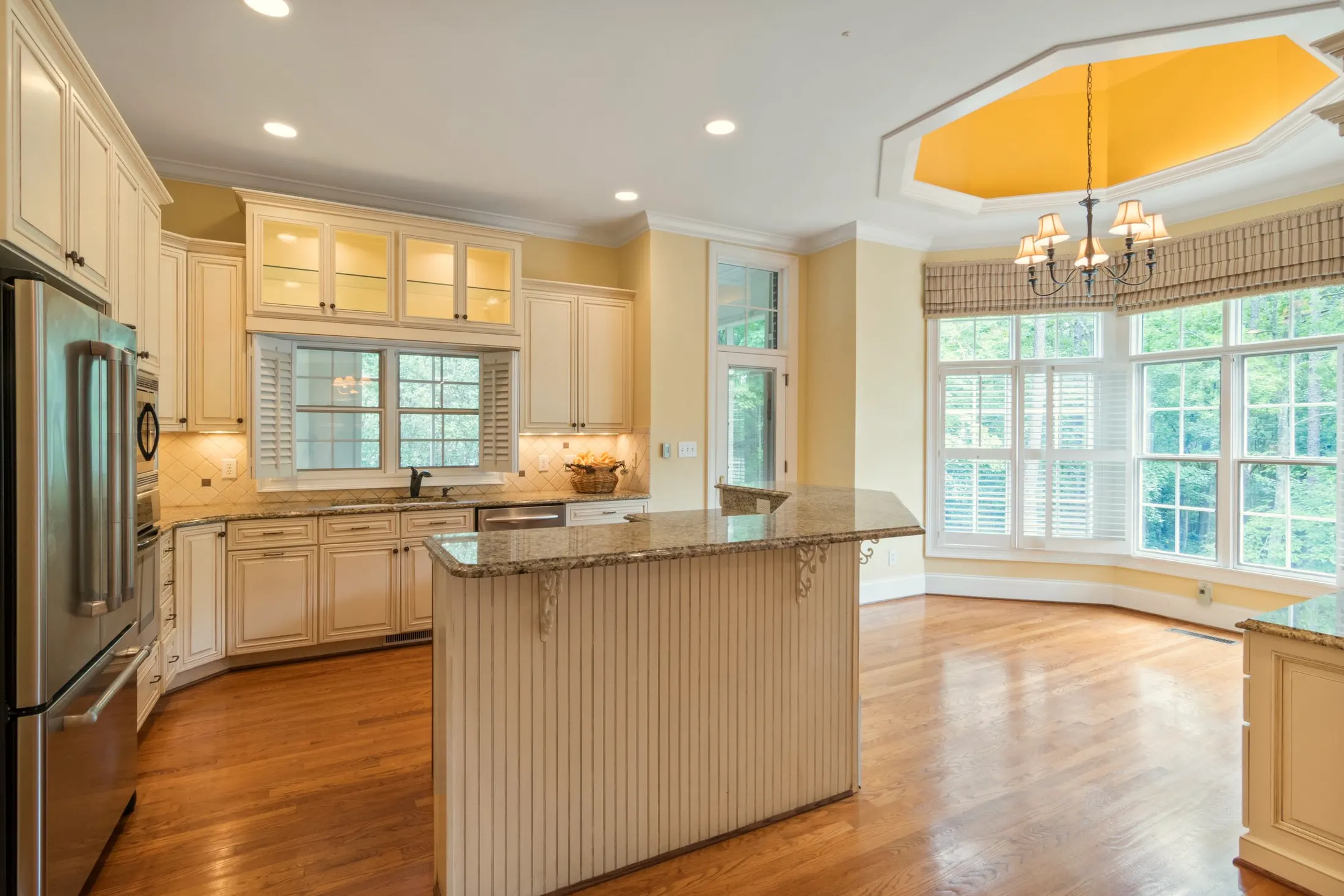 Kitchen with cream cabinets, a center island and a bay of windows under a tray ceiling