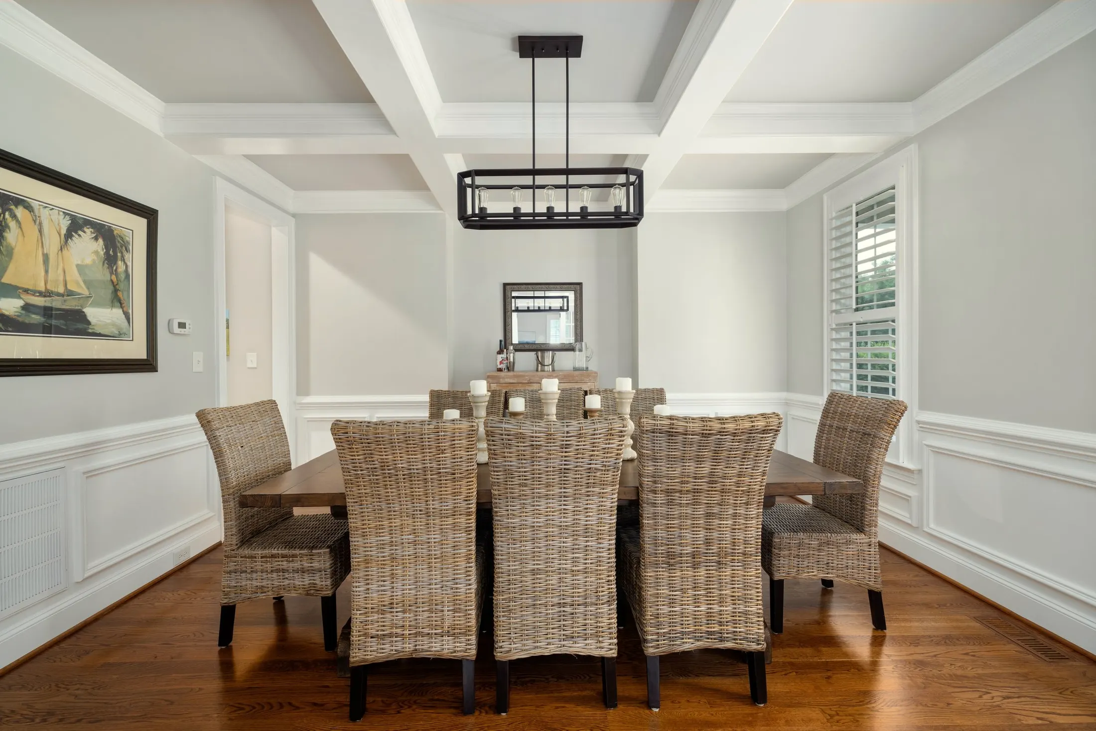 Dining room with a coffered ceiling, paneled walls and a table set for eight