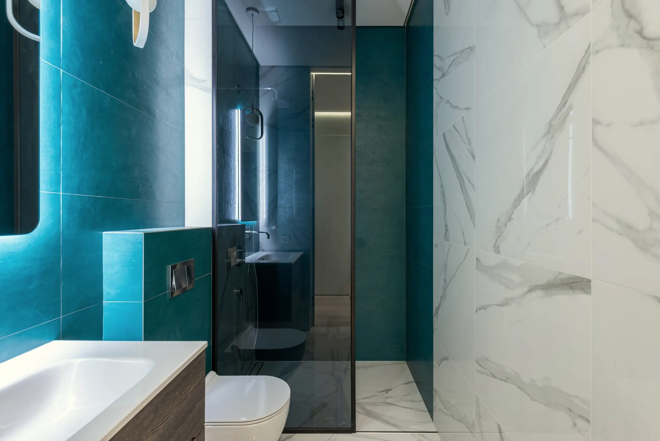 Bathroom with a glass walk-in shower, teal tile and a white marble-look wall