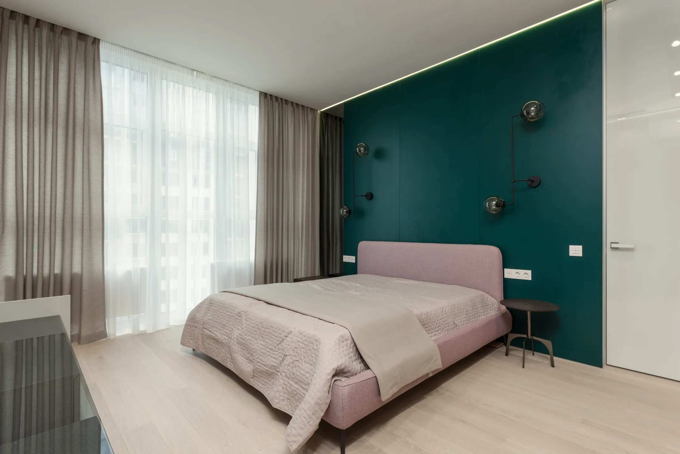 Bedroom with a pink upholstered bed against a teal wall and sheer curtains over a tall window