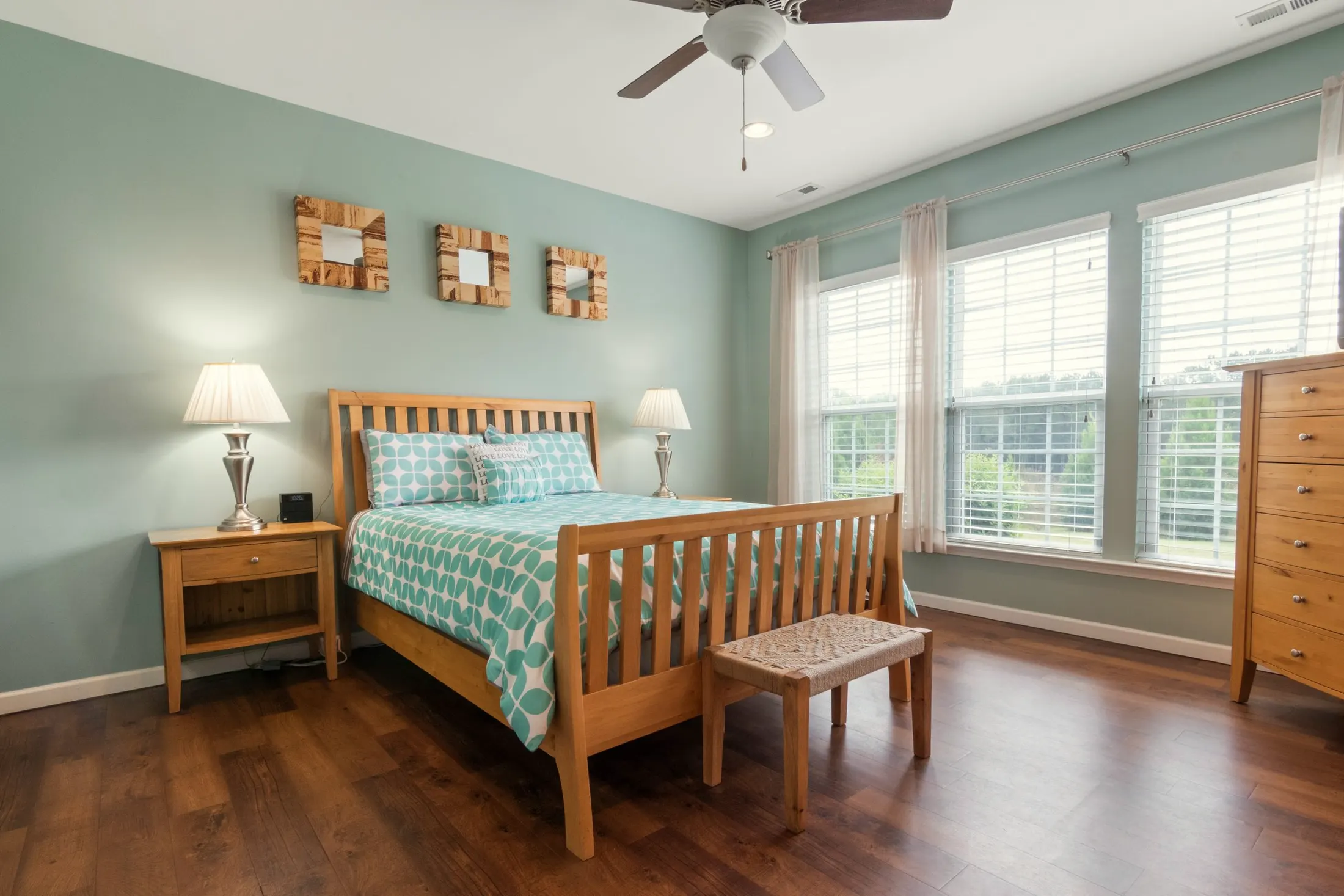Bedroom with sage green walls, a wooden slat bed and tall windows