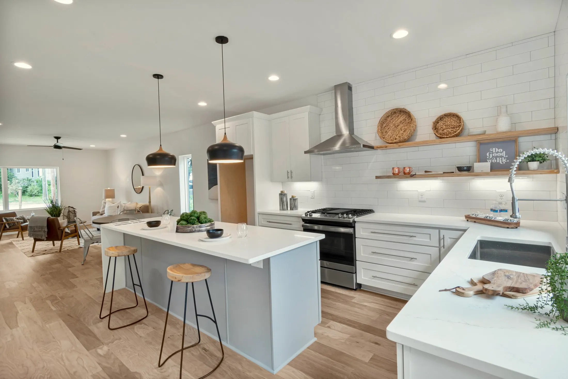 Open kitchen with pendant lights, a white island and a sitting area beyond