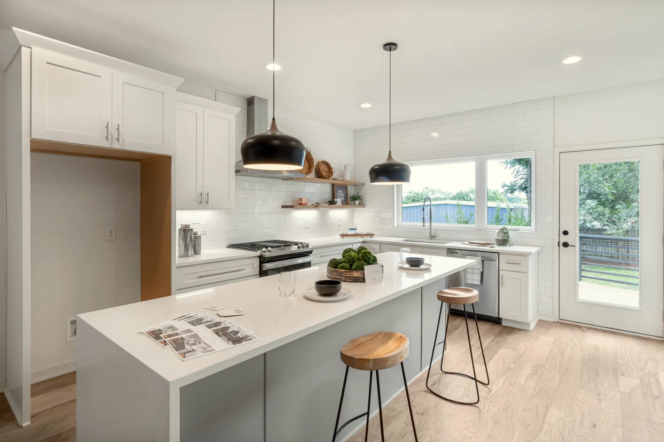 White kitchen island with wooden counter stools, open shelves and a range hood