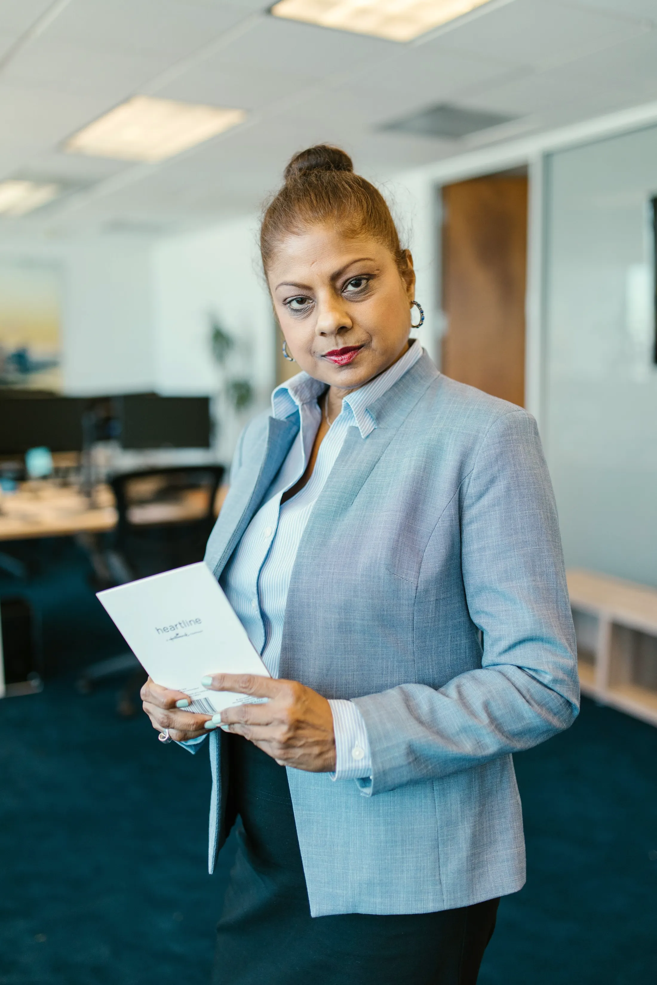 Portrait of a smiling woman in a blazer holding a sheet of paper